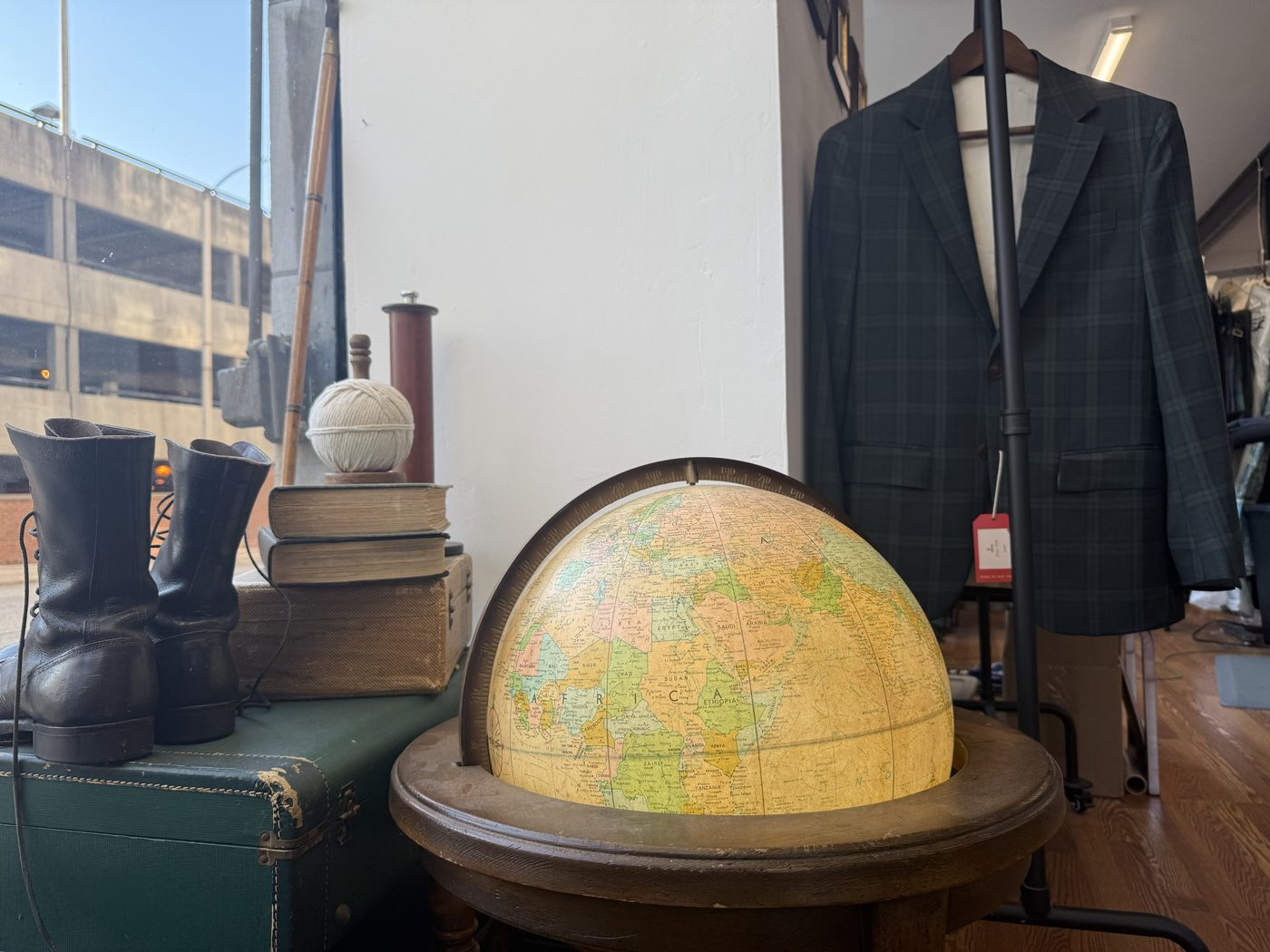 A glowing vintage globe beside a plaid blazer on a rack