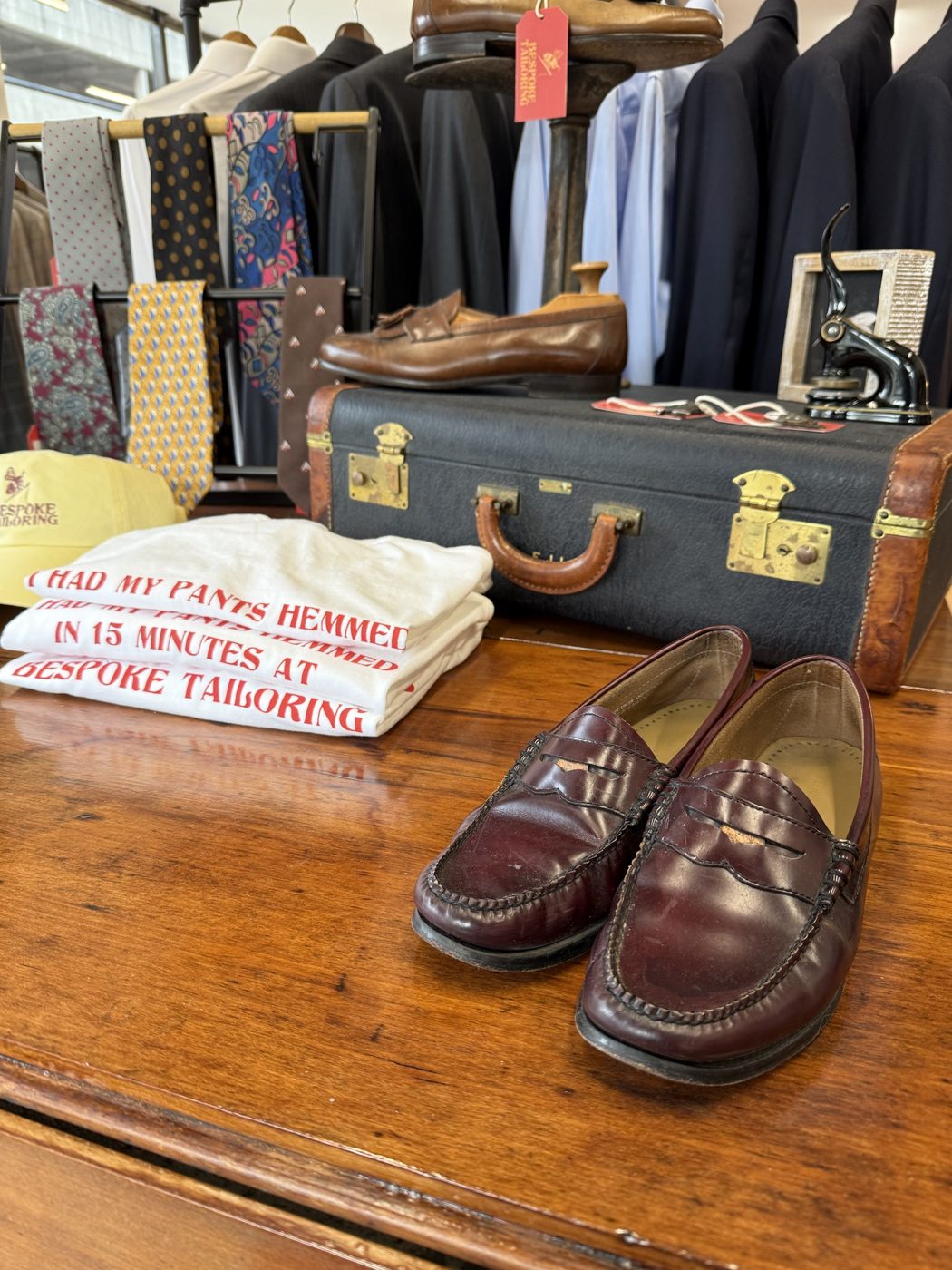 Burgundy loafers and folded Bespoke Tailoring t-shirts on a wooden table